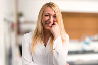 Beyaz gömlek gülümseyen bir tatlı ifadesiyle evde orta yaş sarışın kadınla