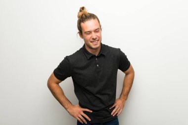 Beyaz duvar mutlu ve gülümseyerek üzerinde uzun saçlı sarışın adam