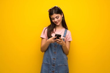 Genç kız üzerinde sarı duvar mobil ileti gönderme