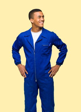 Silah, kalça ile poz ve yalıtılmış zemin üzerine gülen genç afro Amerikan işçi adam