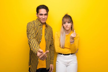 Canlı sarı arka plan üzerinde boynuz jest yapma genç çift