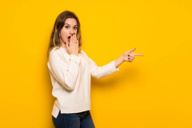 Sarı duvar işaret parmağı bir sürpriz yüz yanında genç kız