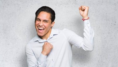 Yakışıklı adam dokulu duvar arka plan üzerinde bir zafer kutluyor