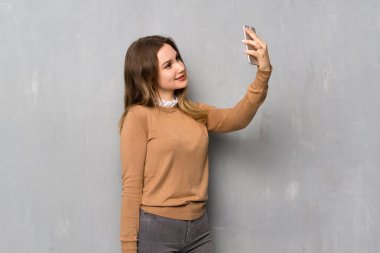 Genç kız bir selfie yapma dokulu duvar üzerinde