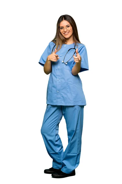 全身年轻的护士指着前面 面带微笑 — 图库照片