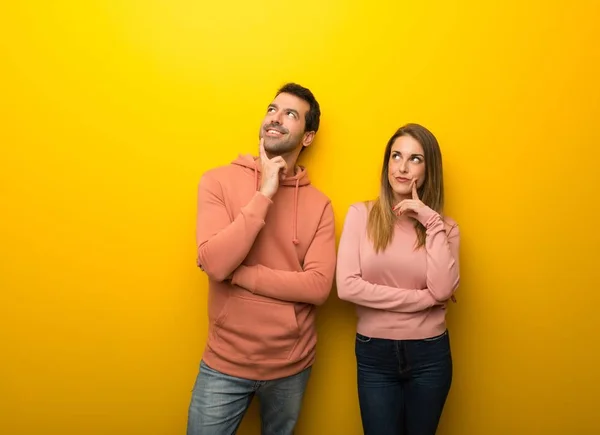 Group of two people on yellow background thinking an idea while looking up