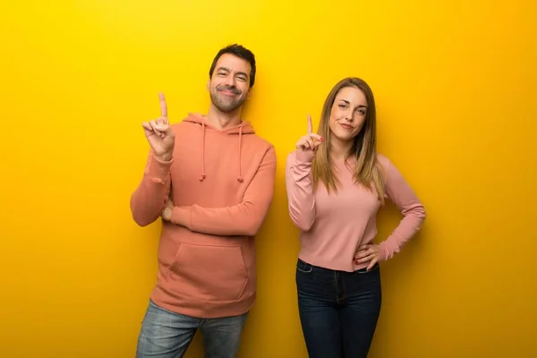 Grupo Duas Pessoas Fundo Amarelo Mostrando Levantando Dedo Sinal Melhor — Fotografia de Stock