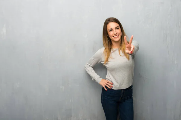Молода Жінка Текстурованій Стіні Посміхається Показує Знак Перемоги — стокове фото