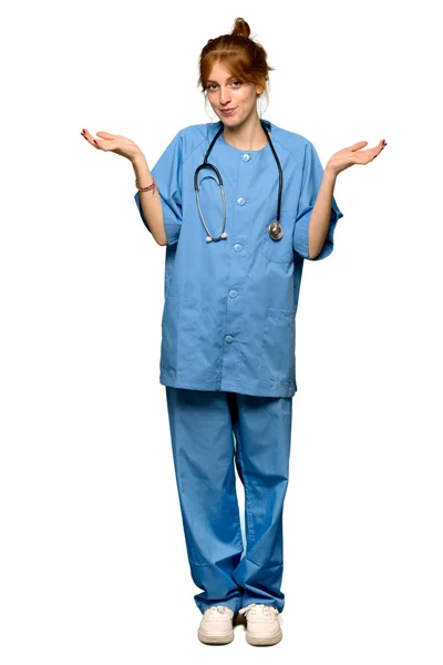 分離の白い背景の上の手と肩を上げながら疑問を持つ赤毛の若い看護師のフルレングス ショット — ストック写真