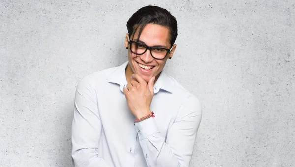 Handsome man with glasses and smiling on textured wall background