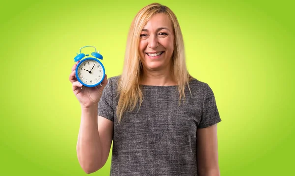 Średnim Wieku Kobieta Blonde Holding Vintage Budzik Kolorowe Tło — Zdjęcie stockowe