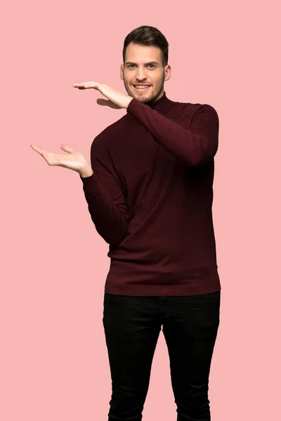 ピンクの背景に広告を挿入する Copyspace のタートルネック セーターを持つ男 — ストック写真