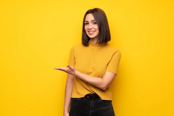 Wanita Muda Atas Dinding Kuning Mempresentasikan Ide Sambil Melihat Arah — Stok Foto