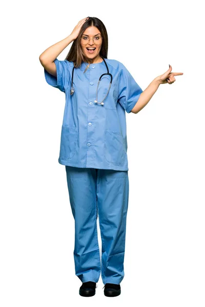 Full body of Young nurse pointing finger to the side and presenting a product