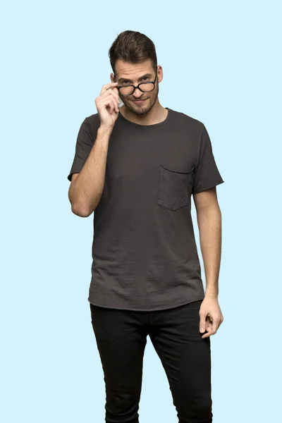 Mężczyzna Czarną Koszulę Okulary Zaskoczony Niebieskim Tle — Zdjęcie stockowe