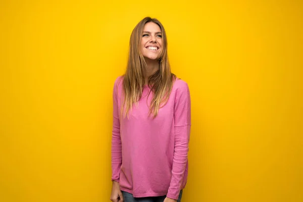 黄色の壁を浮かべて上ピンクのセーターの女性 — ストック写真