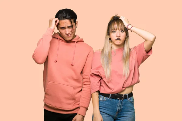 Young couple with an expression of frustration and not understanding over pink background