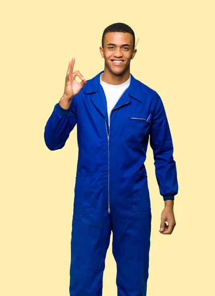 年轻的非洲裔美国工人男子显示一个确定的标志与手指在孤立的背景 — 图库照片
