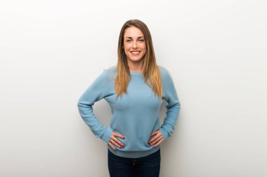 Silah, kalça ile poz ve önüne bakarak gülen izole beyaz arka plan üzerinde sarışın kadın