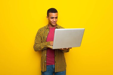 Dizüstü bilgisayar ile sarı zemin üzerine genç afro Amerikalı adam