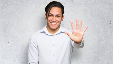 Yakışıklı adam dokulu duvar arka plan üzerinde parmakları ile beş sayma