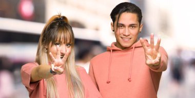 Genç çift mutlu ve şehirde parmakları ile üç sayma