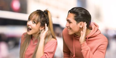 Genç çift şehirde kulağına el koyarak bir şey dinliyor