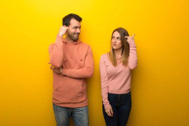 Grup parmak kafasına koyarak delilik jest yaparak sarı zemin üzerine iki insan