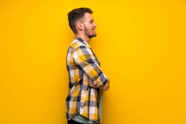 Lateral pozisyonda sarı duvarın üzerinden yakışıklı adam