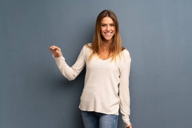 Gülümseyen gri arka plan üzerinde sarışın kadın