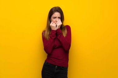 Gergin ve korkmuş ellerini ağzına koyarak sarı duvarın üzerinden balıkçı yaka kadınla