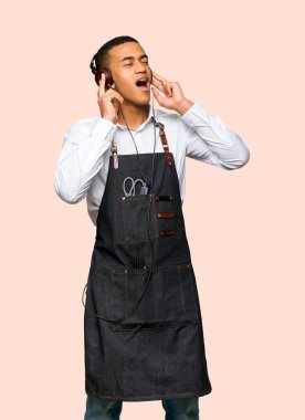 Genç afro Amerikan Kuaför adam izole arka plan üzerinde kulaklık ile müzik dinlemek