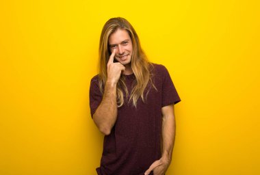 Sarı duvarın önüne bakarak üzerinden uzun saçlı sarışın adam