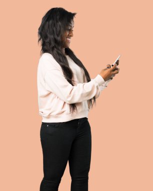 Genç afro Amerikalı kadın izole kahverengi zemin üzerinde mobil ileti gönderme