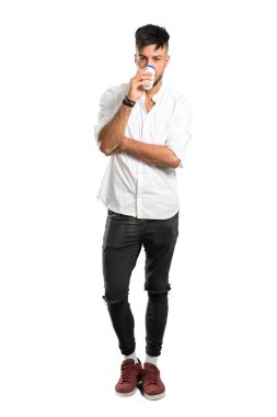 Beyaz gömlekli, beyaz gömlekli, izole edilmiş beyaz arka planda, kağıt bardakta sıcak kahve tutan Arap bir gencin tam boy fotoğrafı.