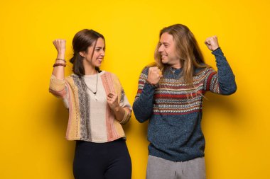 Hippi çift bir zaferini kutluyor sarı arka plan üzerinde