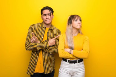 Canlı sarı arka plan üzerinde genç çift şüpheleri olan laterals işaret