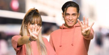 Genç çift mutlu ve şehirde parmakları ile dört sayma