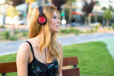 Genç ve güzel genç kız bir parkta kulaklık ile müzik dinlemek