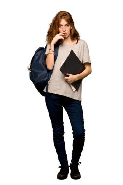 İzole beyaz arka plan üzerinde ararken şüpheleri bir genç redhead öğrenci tam uzunlukta bir kadeh