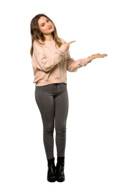 İzole beyaz arka plan üzerinde bir reklam eklemek için bir genç kızla pembe kazak boşaltmak hayali avuç içinde tutarak tam uzunlukta bir kadeh