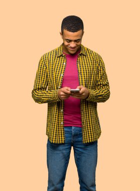 Genç afro Amerikalı adam izole arka plan üzerinde mobil ileti gönderme