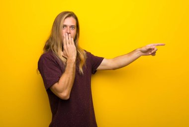 Üzerinde sarı uzun saçlı sarışın adam şaşırmış bir yüz yanında işaret parmağı duvar