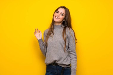 Üzerinde sarı duvar gülümseyen genç kadın