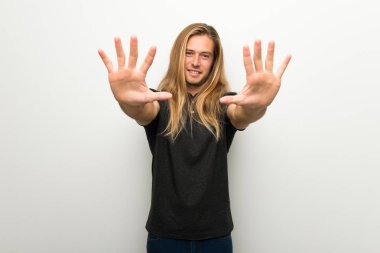 Beyaz duvar on parmak ile sayma üzerinde uzun saçlı sarışın adam