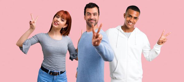 Group of three friends smiling and showing victory sign