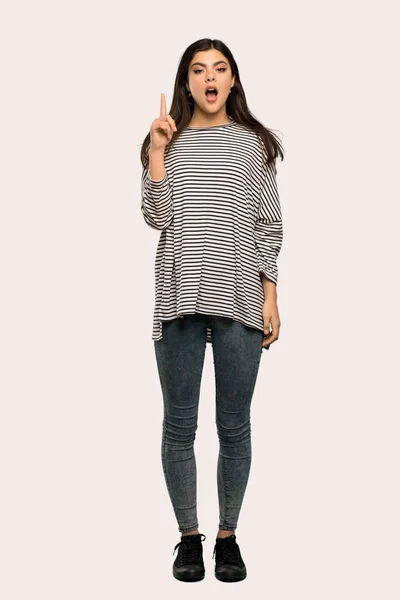 孤立した背景の上指を指してアイデアを考えてのストライプのシャツとティーンエイ ジャーの女の子のフルレングス ショット — ストック写真