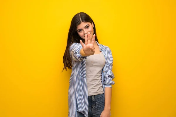 黄色の壁幸せとカウント 本の指で上のティーンエイ ジャーの女の子 — ストック写真