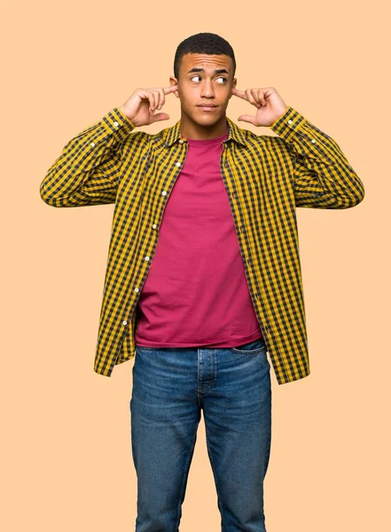 Genç afro Amerikalı adam her iki kulak izole arka plan üzerinde elleriyle kapsayan