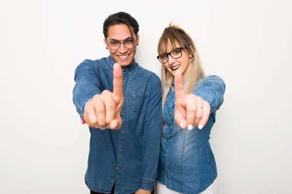 Young couple with glasses showing and lifting a finger